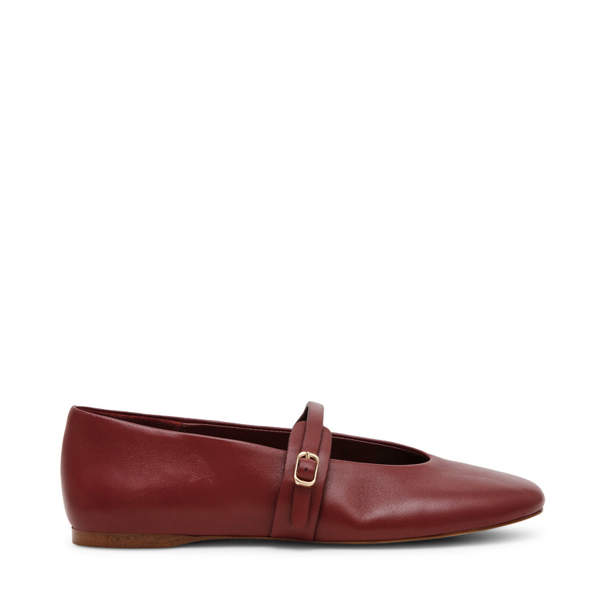 A red flat shoe with a Mary Jane strap and buckle closure.